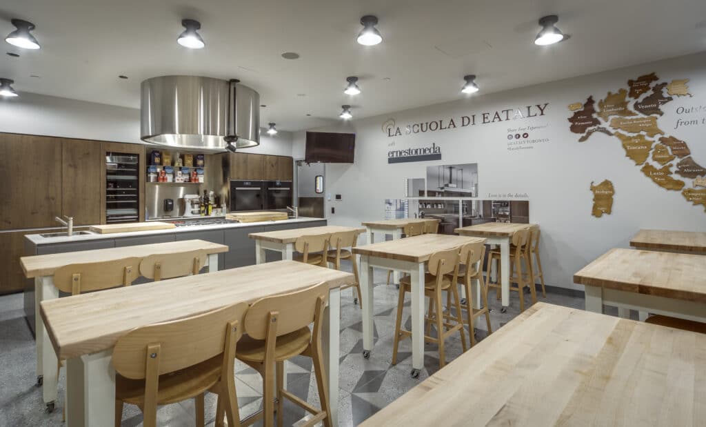 Image of wooden tables with chairs inside of a room used for La Scuola Di Eataly cooking classes.